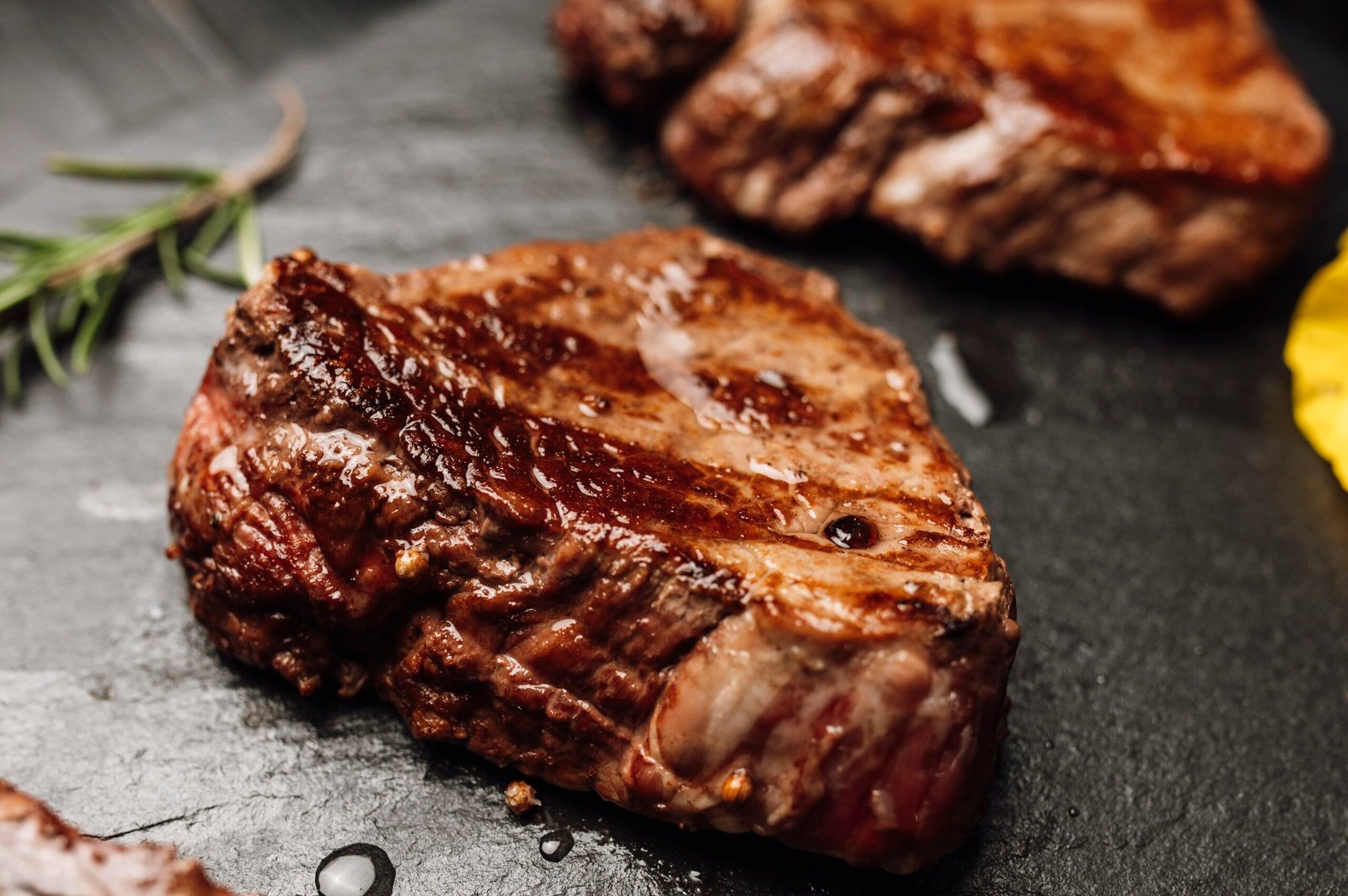 Grilled steak on black slate with herbs ready for serving